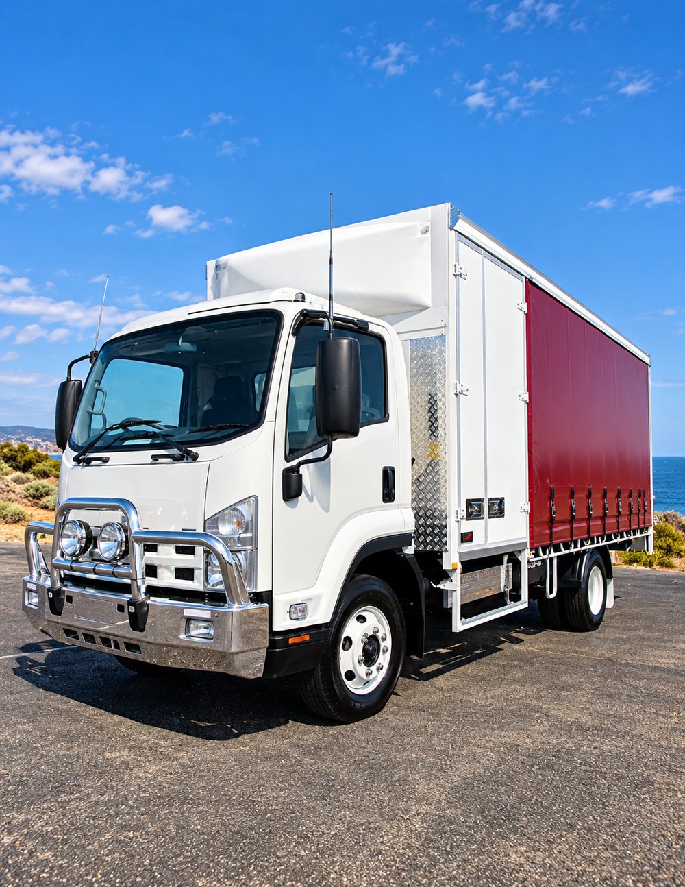 Chrome curtain-side truck on a coastal road